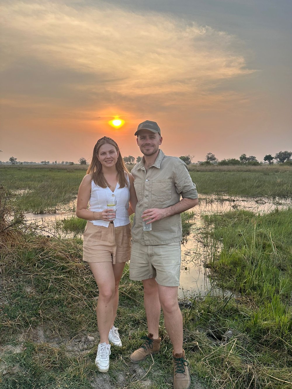 Callum and his partner standing together at sunset in a marshy wetland landscape