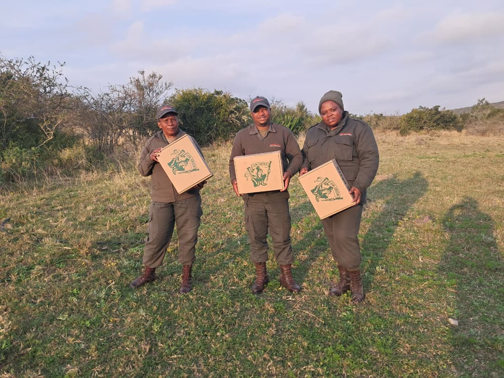 Three field rangers displaying their Boots for Rangers boxes in the field